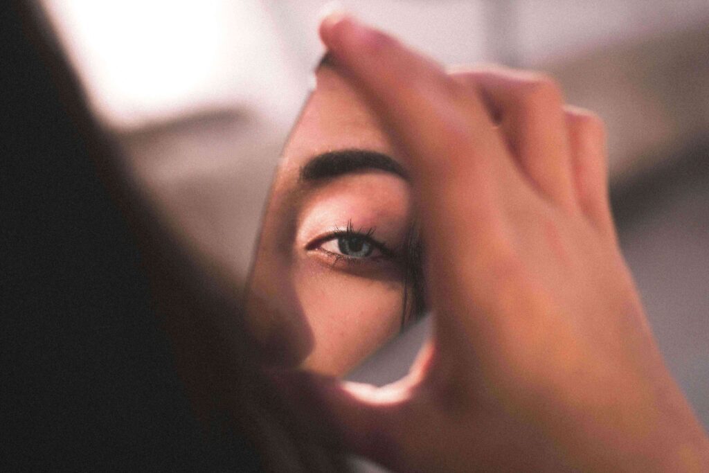 The Eye Wearhouse Olds facial treatment woman looking itno mirror