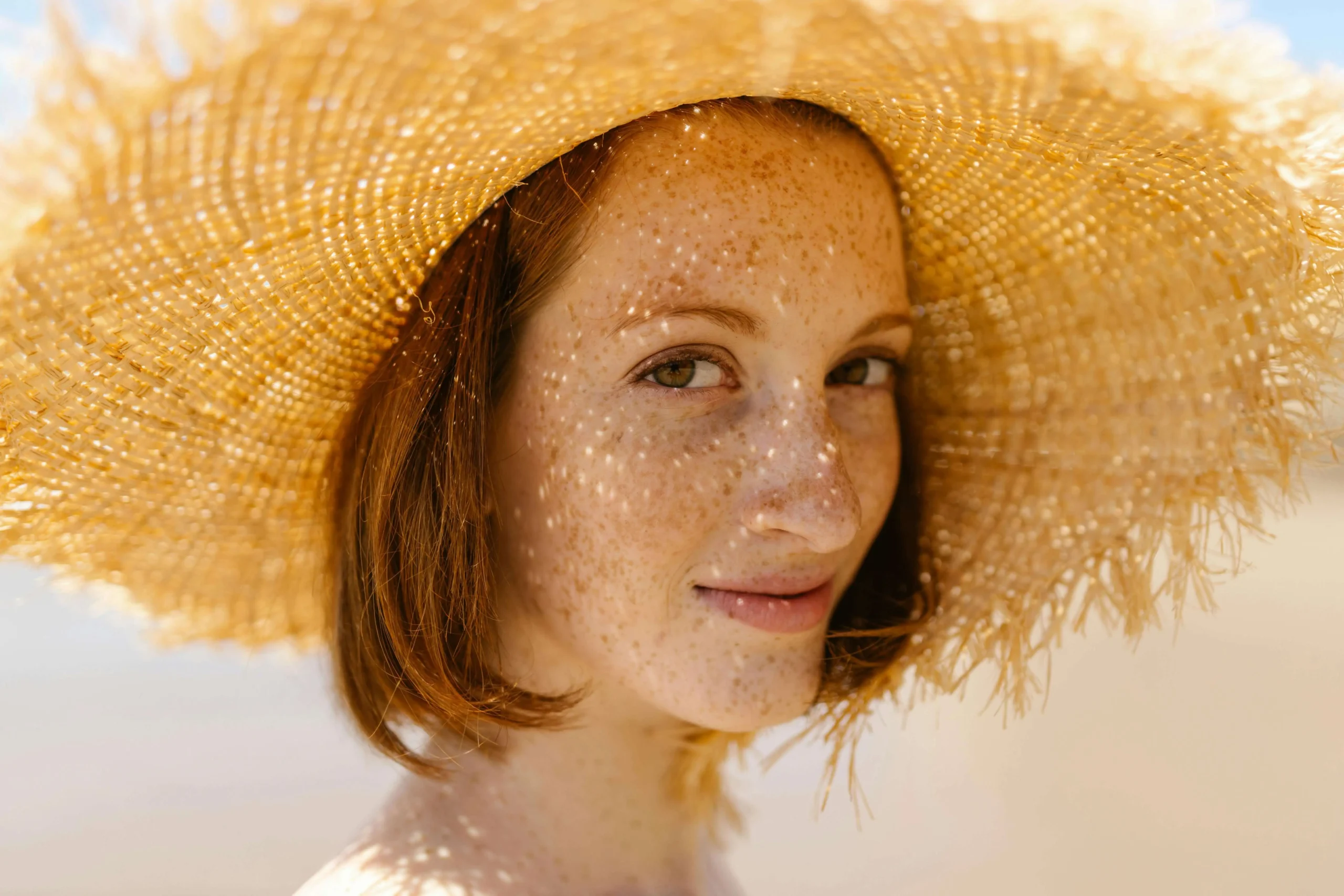 woman with straw hat hyperpigmentation and sun damage the eye wearhouse
